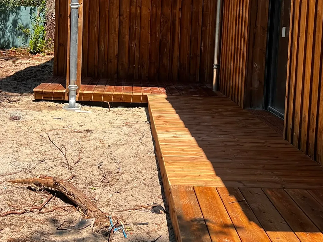 Angle de la terrasse bois au pied du bardage, sous l’avancée de toiture