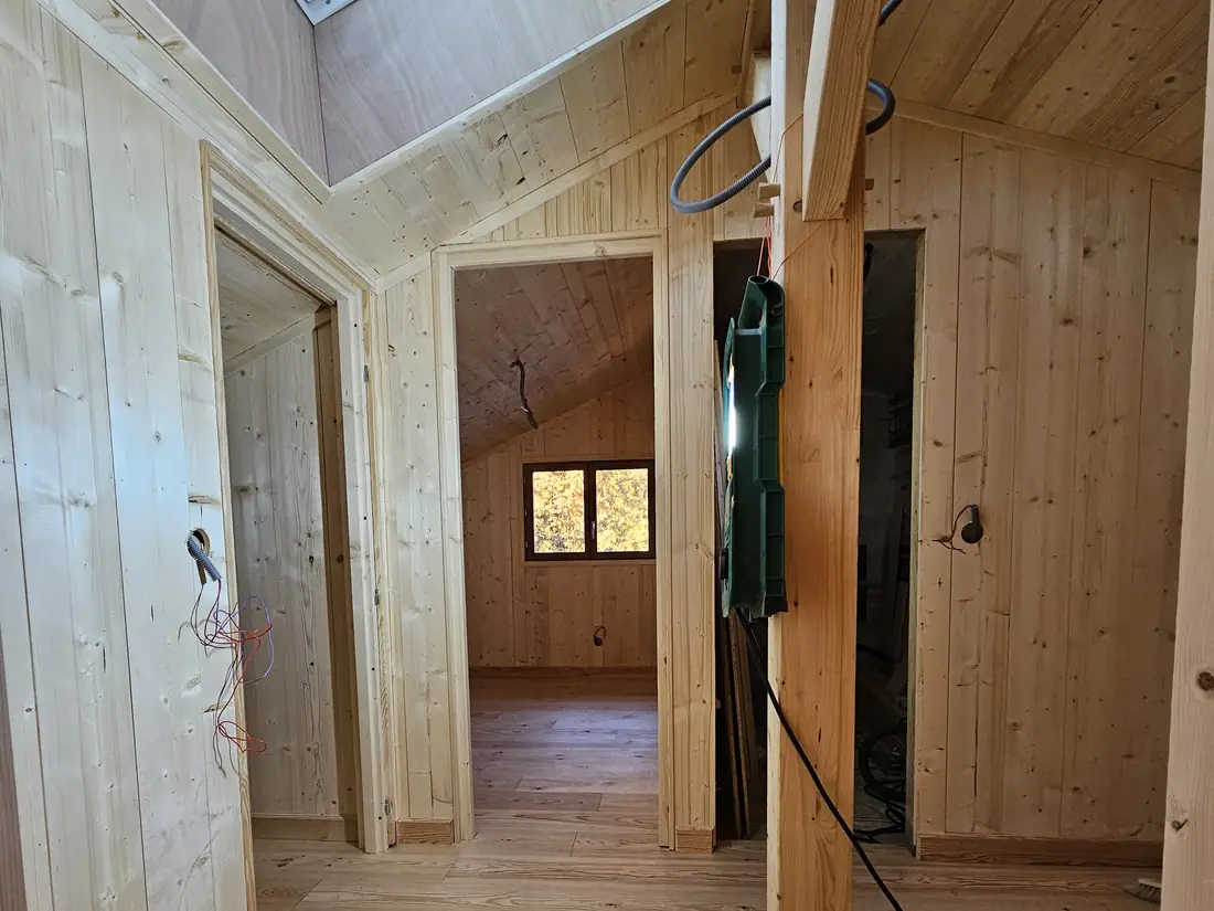 Circulation de l’étage éclairée par une fenêtre de toit, habillage bois et plancher posé