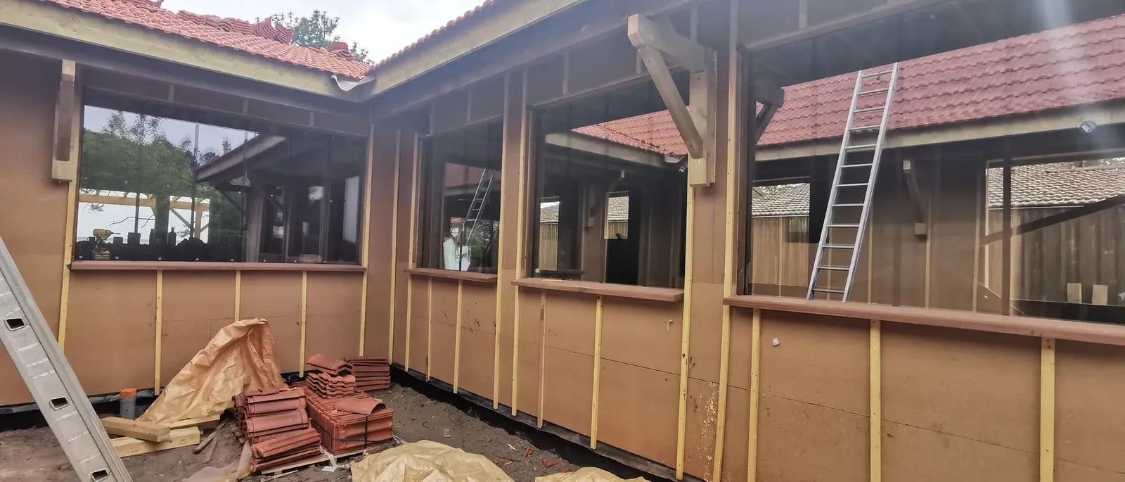 Extension bois en cours de montage autour d’une maison existante