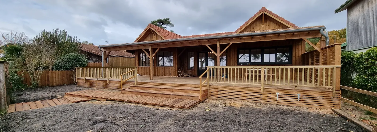 Maison à ossature bois livrée, avec sa terrasse couverte, son platelage et ses garde-corps bois
